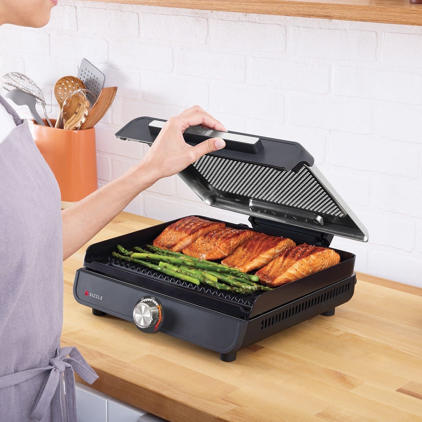 Ninja-GR101UK-InUse-Kitchen-OnCounter-SmokeGuardSystem-SalmonGrilledAsparagus-Woman-RGB